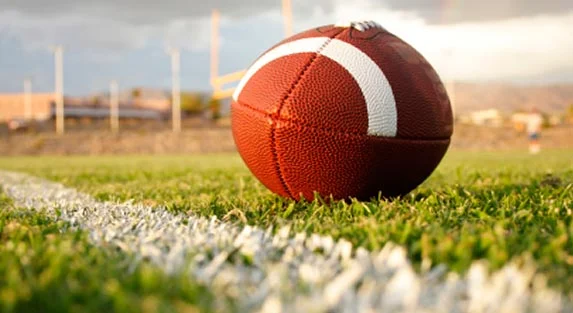 A football rests on the grass near a field marking.