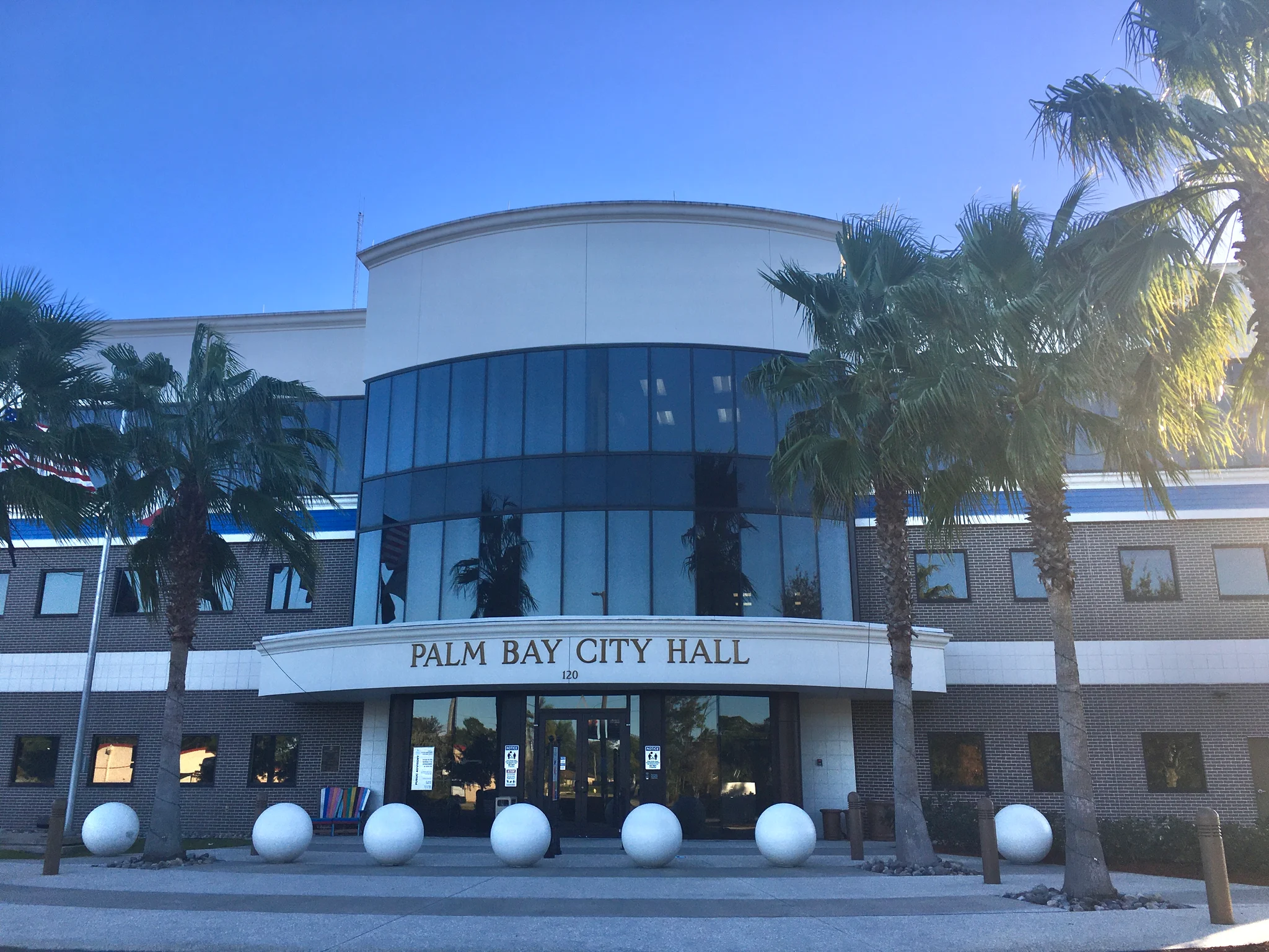 Palm trees frame the glass-fronted entrance marked Palm Bay City Hall.