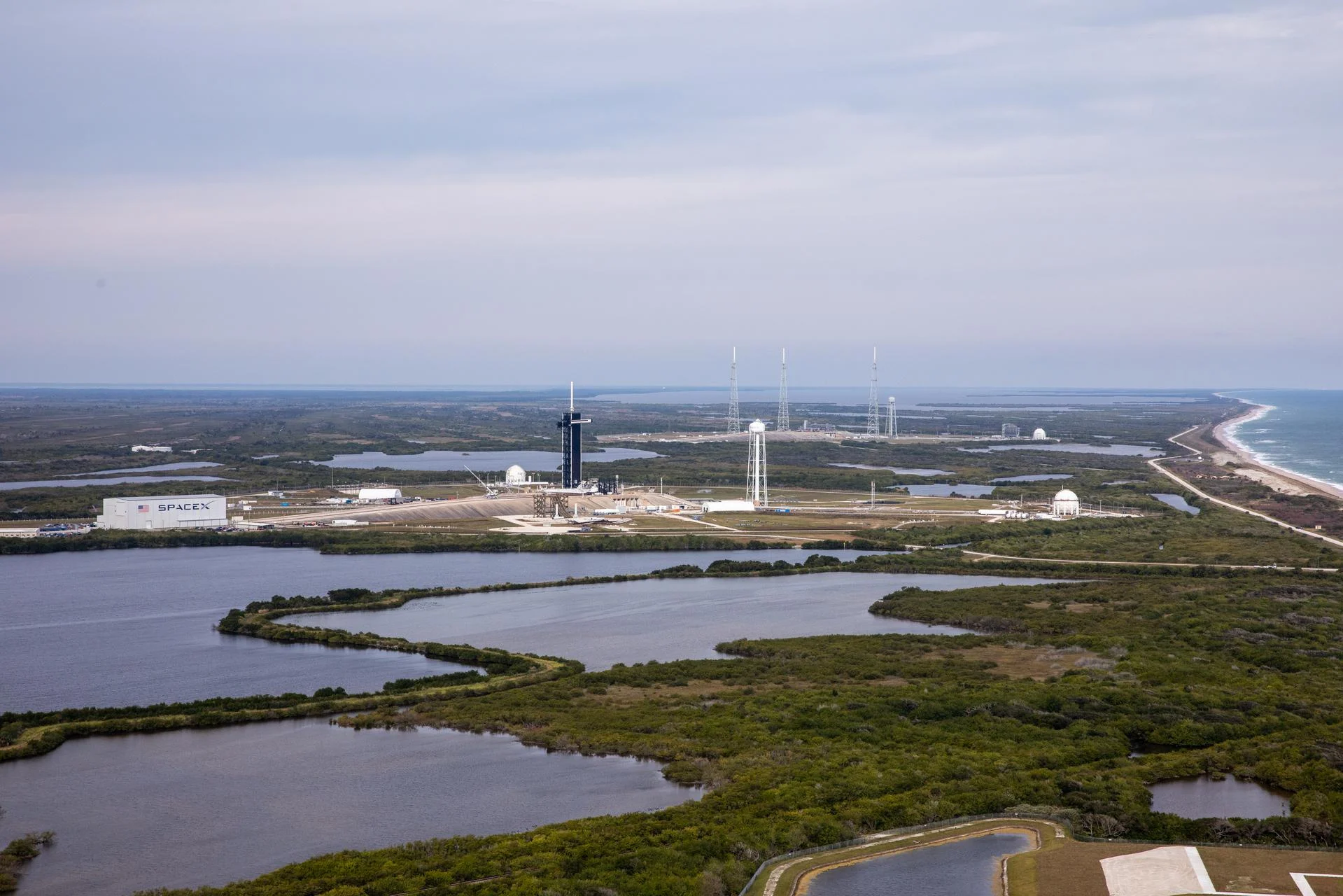 Aerial view of launch pads beside wetlands and the Atlantic coast at Kennedy Space Center.